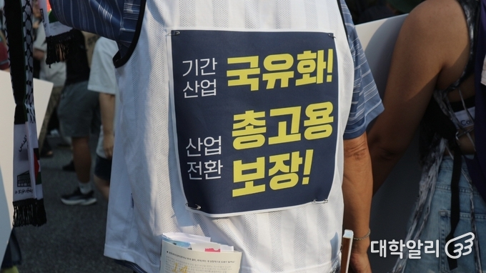 행진 참여자가 노동자 총고용 보장을 촉구하는 문구가 적힌 종이를 옷에 걸고 행진하고 있다. <strong>이선영 기자</strong>