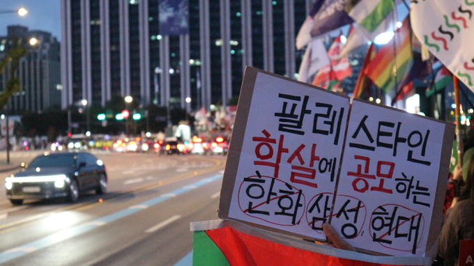 팔레스타인을 향한 집단학살에 공모한 기업을 규탄하기 위해 행진 참가자가 손에 든 피켓 <strong>이선영 기자</strong>